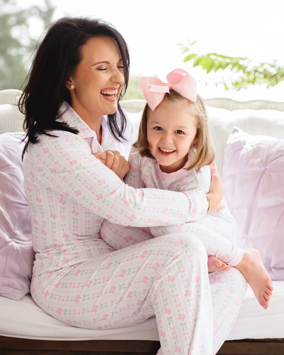 Woman and child in matching pajamas sitting on a couch