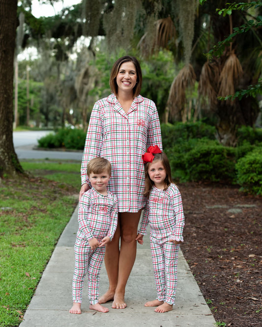 Woman and two children in matching plaid pajamas standing outdoors on a path.