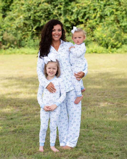 Woman and two children wearing matching pajamas in a grassy field.