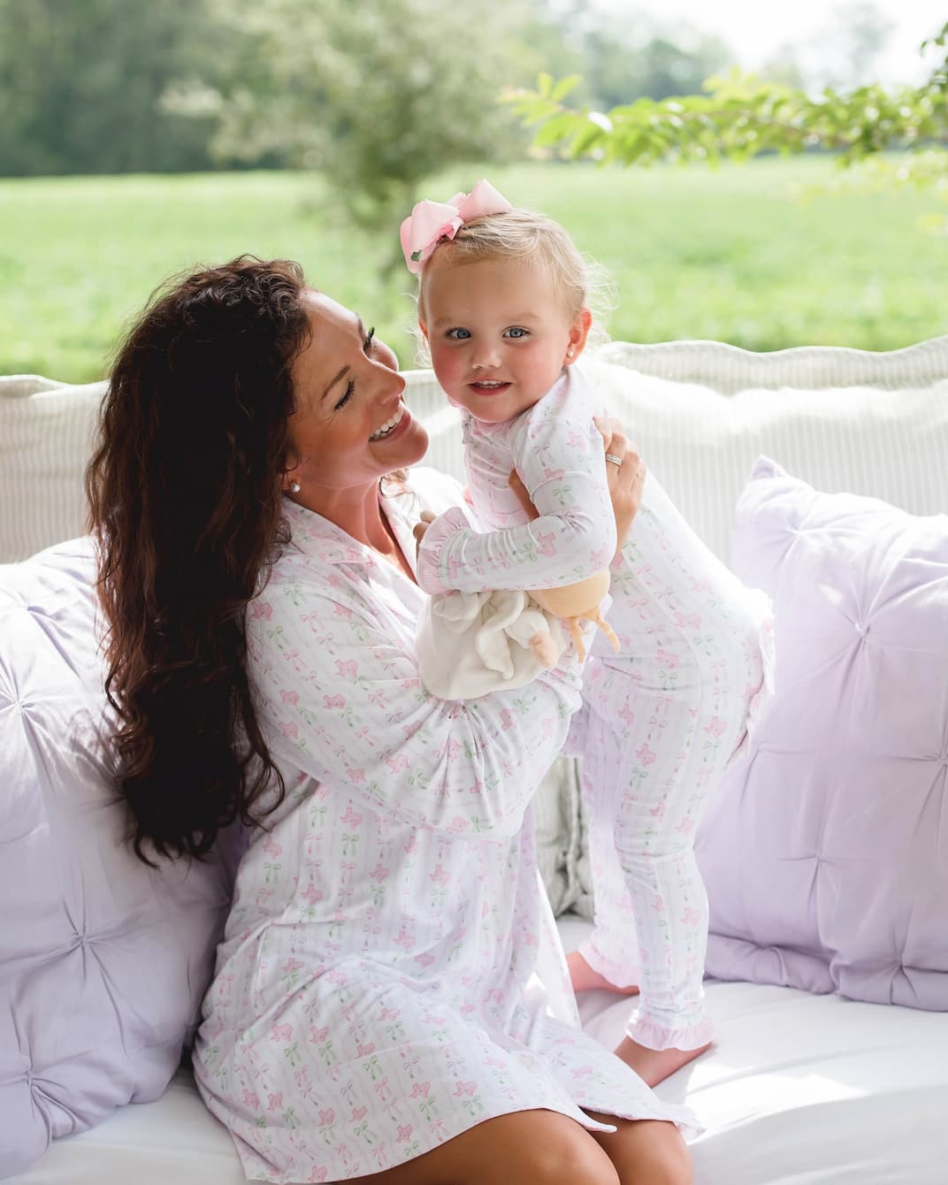 Woman holding a baby on a white couch outdoors