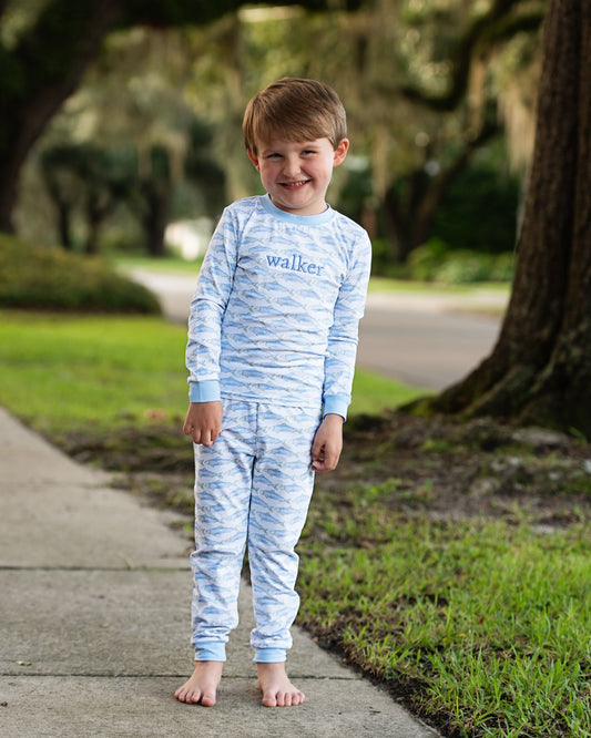 Young boy wearing a blue and white striped outfit with 'walker' printed on it, standing outdoors.
