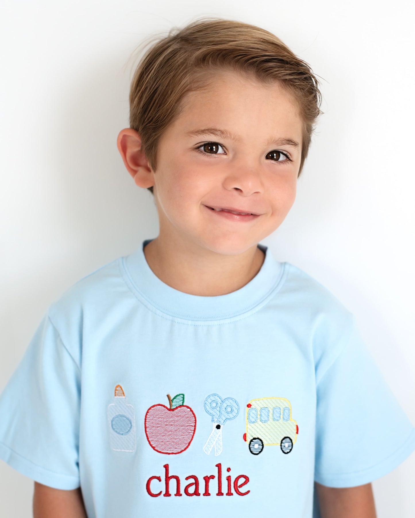 Young boy wearing a blue school themed shirt.