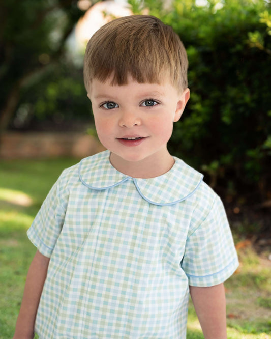 Young boy wearing a checkered shirt with a collar outdoors