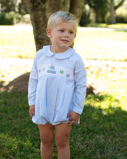 Young boy wearing a light blue outfit with embroidered designs outdoors.