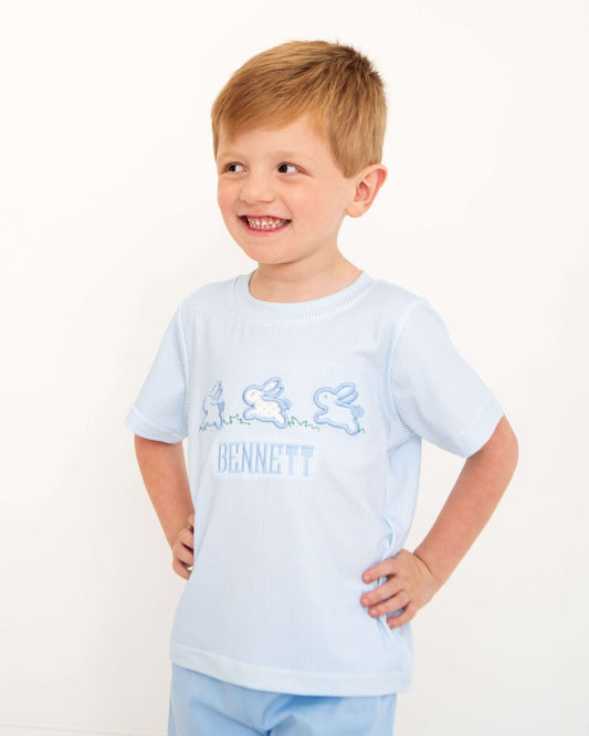 Young boy wearing a light blue t-shirt with a logo on a white background