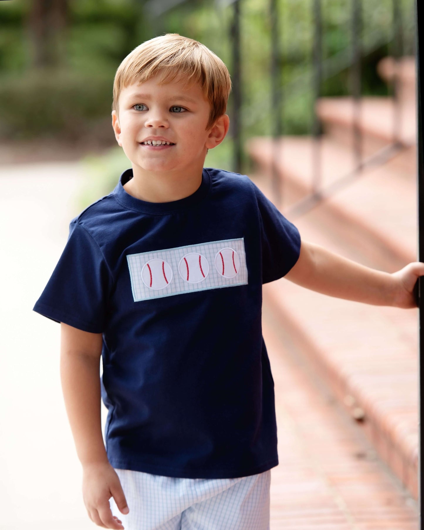 Young boy wearing a navy blue t-shirt with a white graphic design outdoors.