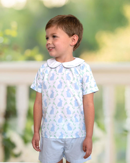 Young boy wearing a patterned shirt and shorts outdoors