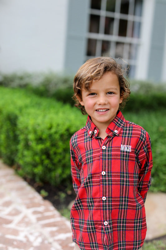 Young boy wearing a red plaid shirt with initials 'MKH' on it, standing outdoors.