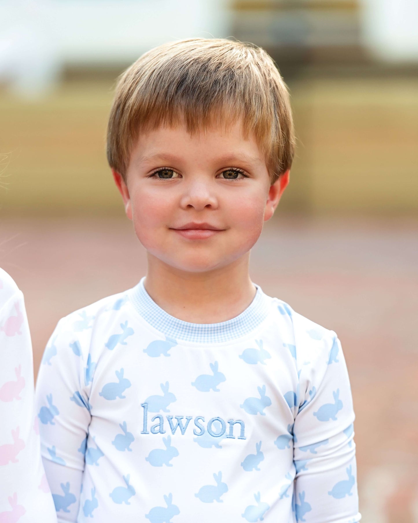 Young boy wearing a shirt with 'lawson' printed on it, standing outdoors.