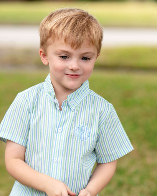 Young boy wearing a striped shirt outdoors with a blurred natural background