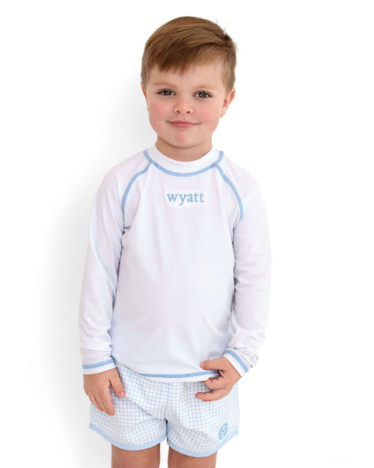 Young boy wearing a white long-sleeve shirt and checkered shorts with 'wyatt' printed on the shirt.
