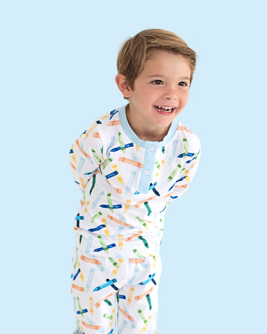 Young boy wearing pajamas with crayons print.