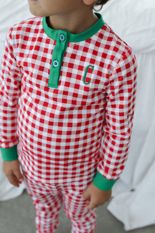 Young boy wearing red checked pajamas with green trim and a single letter monogram