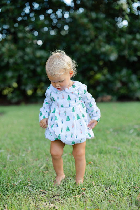 Young child in a dress with tree pattern standing on grass