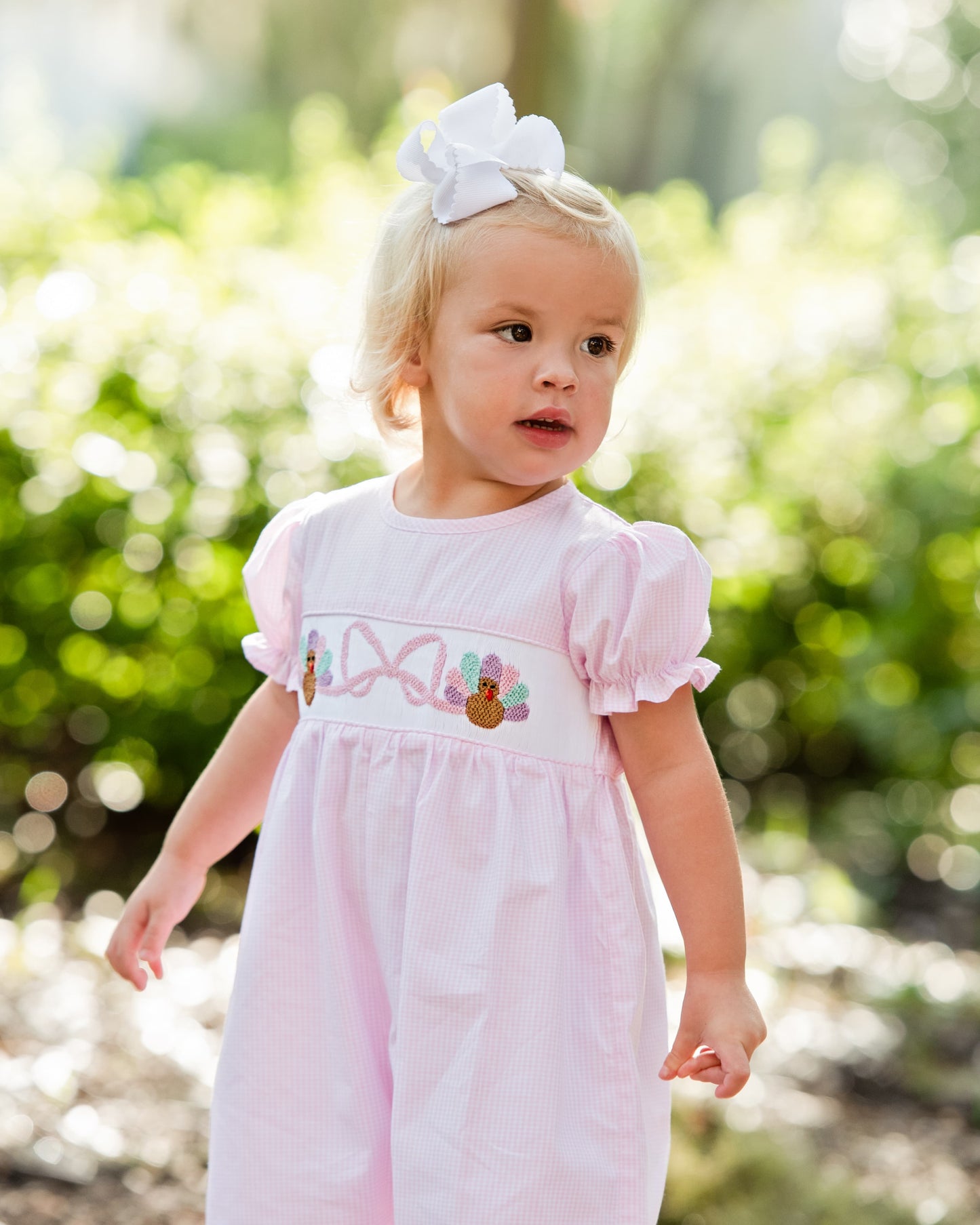Young child wearing a pink long bubble with turkey