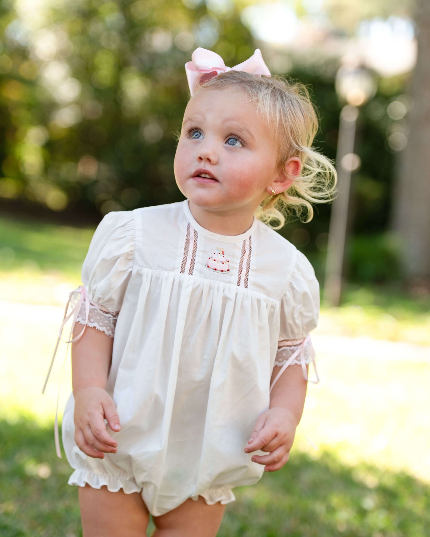 Young child wearing a white dress with pink trim outdoors