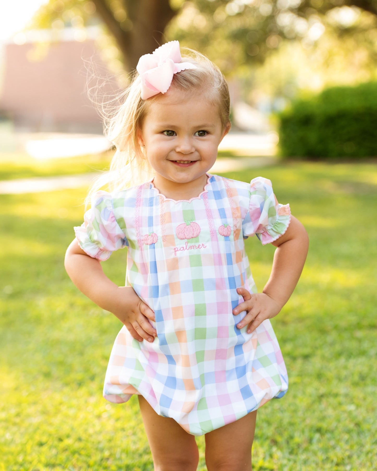 Young girl in a checkered bubble standing outdoors on grass