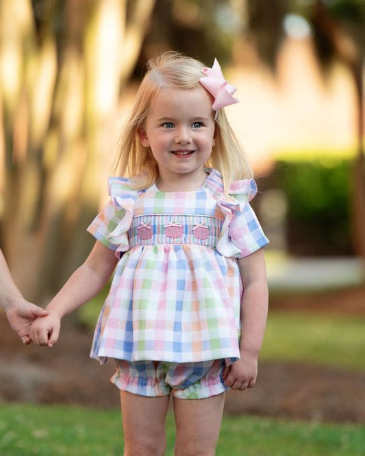 Young girl in a colorful checkered diaper set with a blurred outdoor background