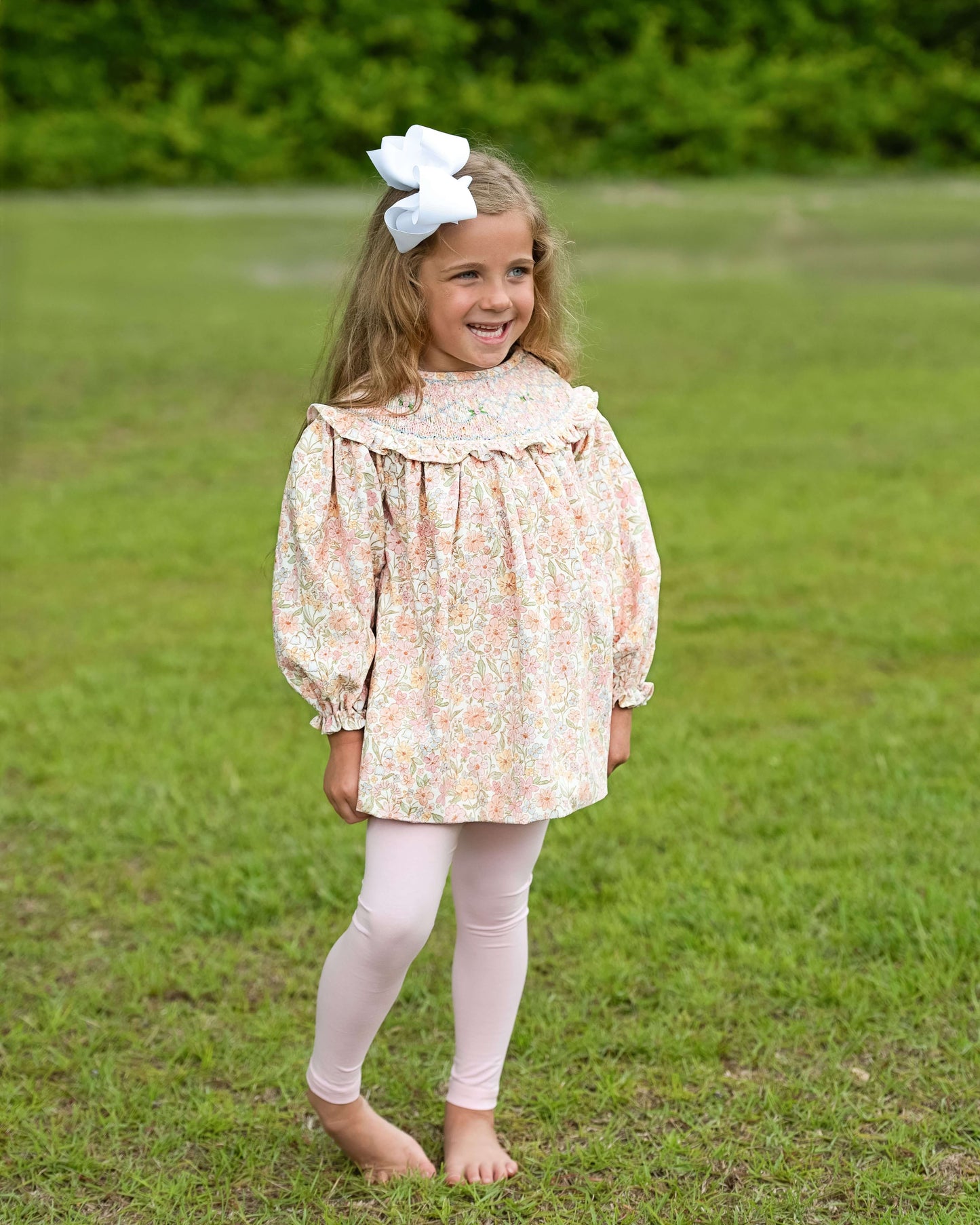 Young girl in a floral dress standing in a grassy field