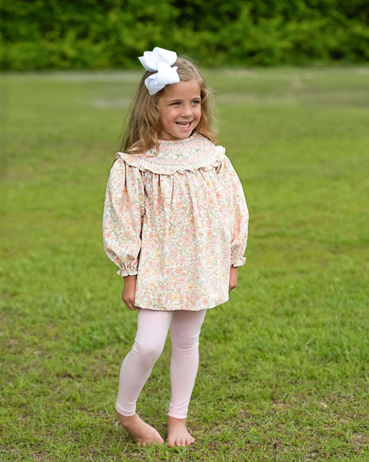 Young girl in a floral dress standing in a grassy field