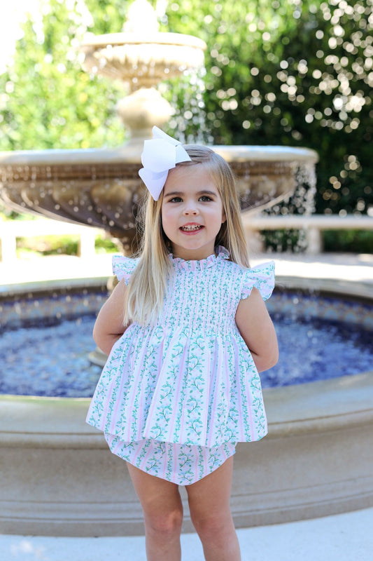 Young girl in a floral dress standing in front of a fountain