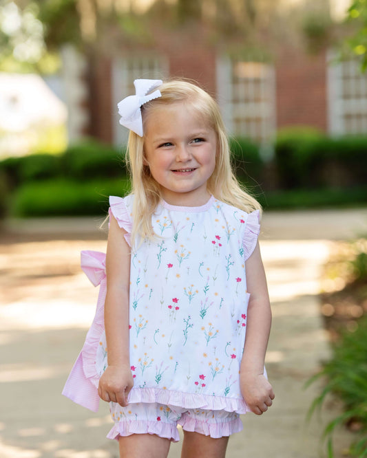 Young girl in a floral dress with a large white bow outdoors