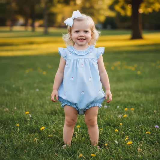 Young girl in a light blue dress standing in a grassy field with flowers.