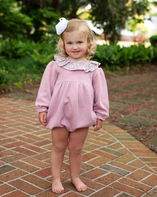 Young_girl_in_a_pink_bubble_with_a_floral_collar_standing_on_a_brick_path._1_2_1
