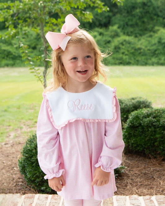 Young girl in a pink dress with a large bow outdoors
