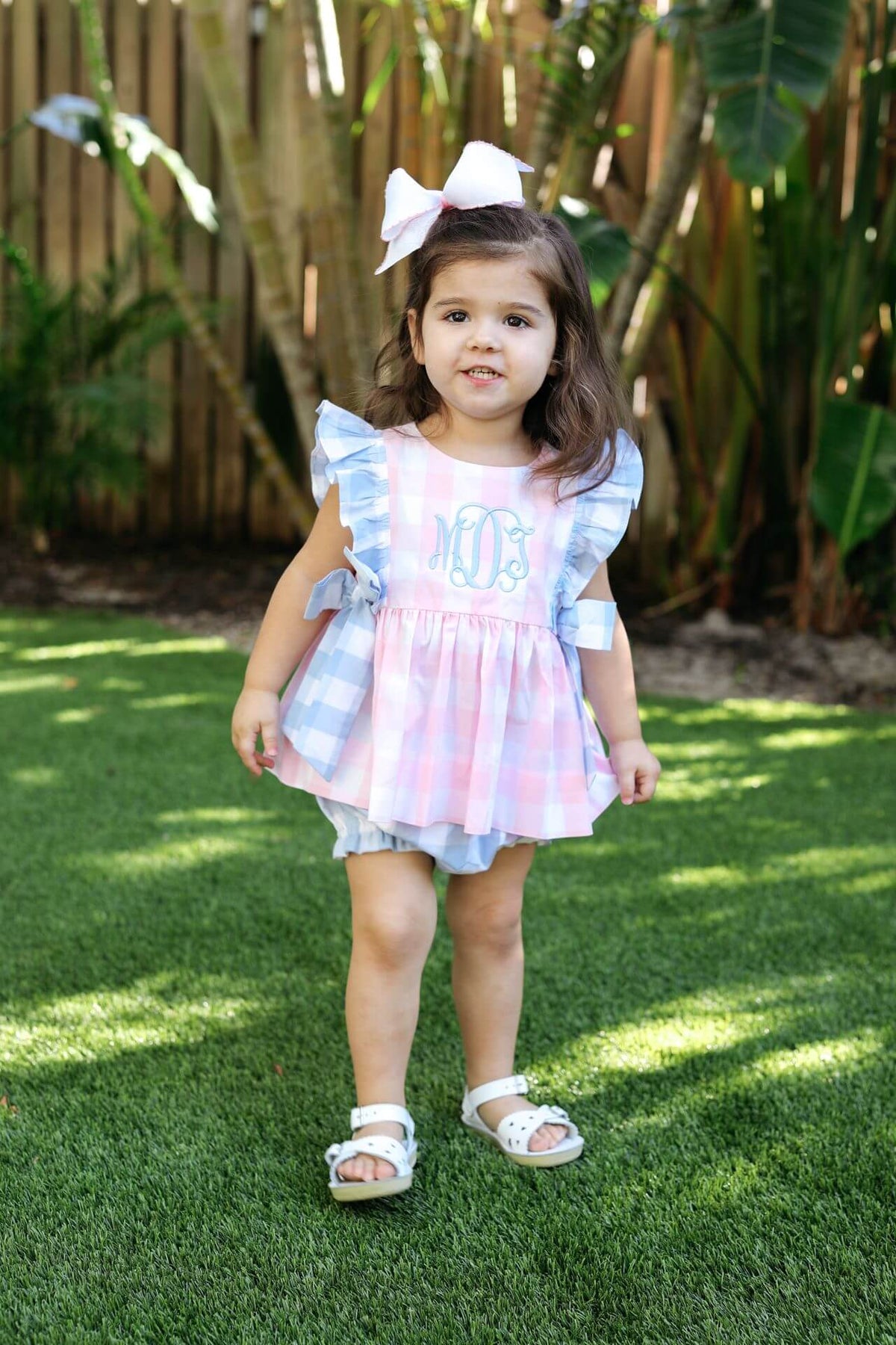 Young girl in a pink dress with ruffled sleeves standing on grass