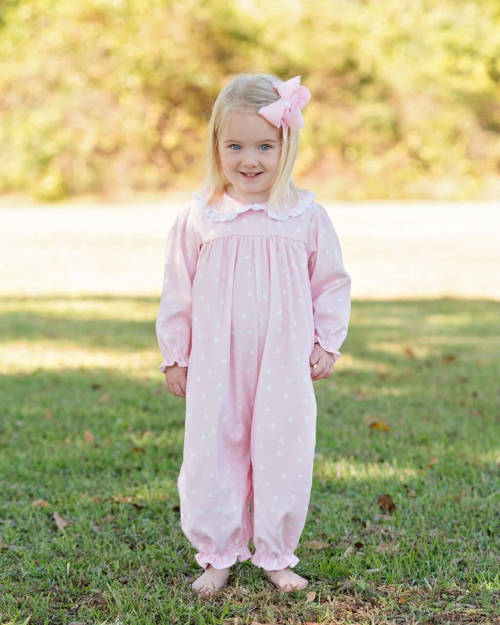 Young girl in a pink heart long bubble with a bow standing on grass