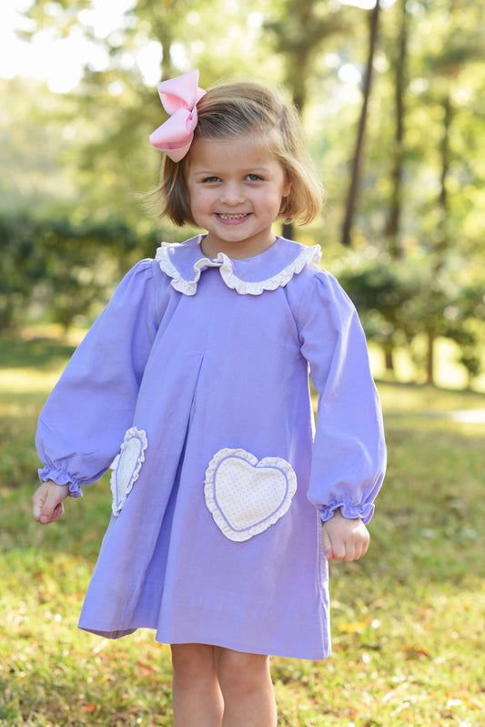 Young girl in a purple dress with white heart designs outdoors