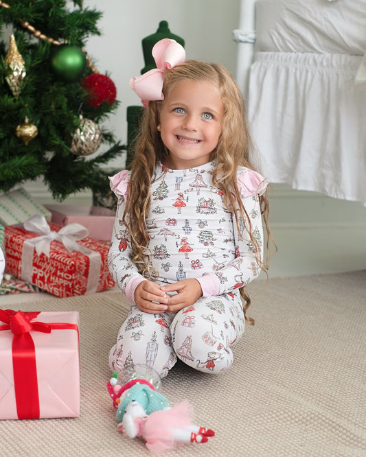 Young girl in pajamas sitting on the floor with Christmas decorations in the background