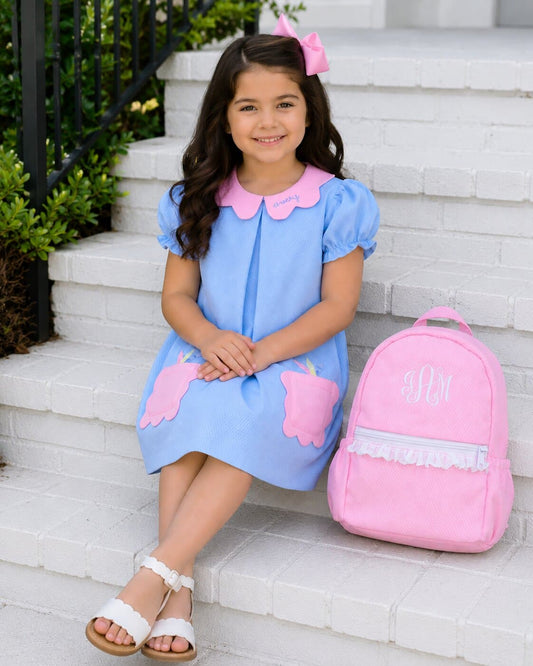 Young girl sitting on some steps next to a backpack