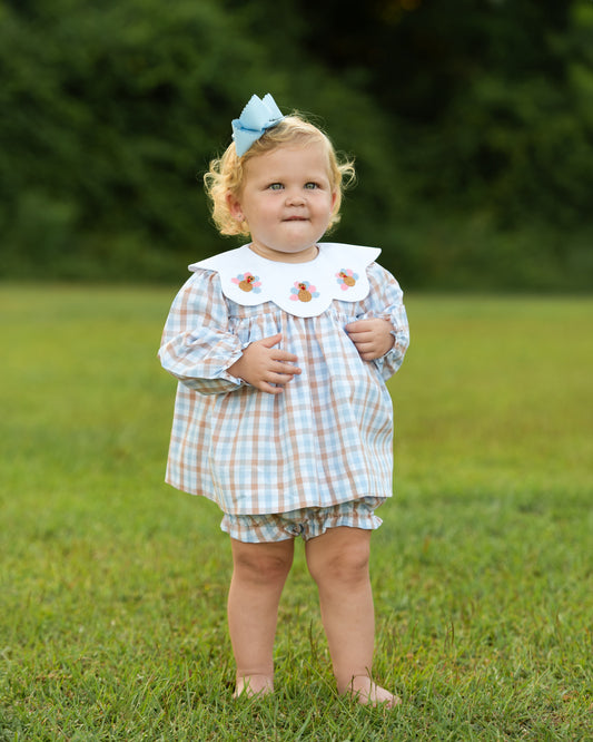 Young girl wearing a blue and brown check embroidered Turkeys diaper set