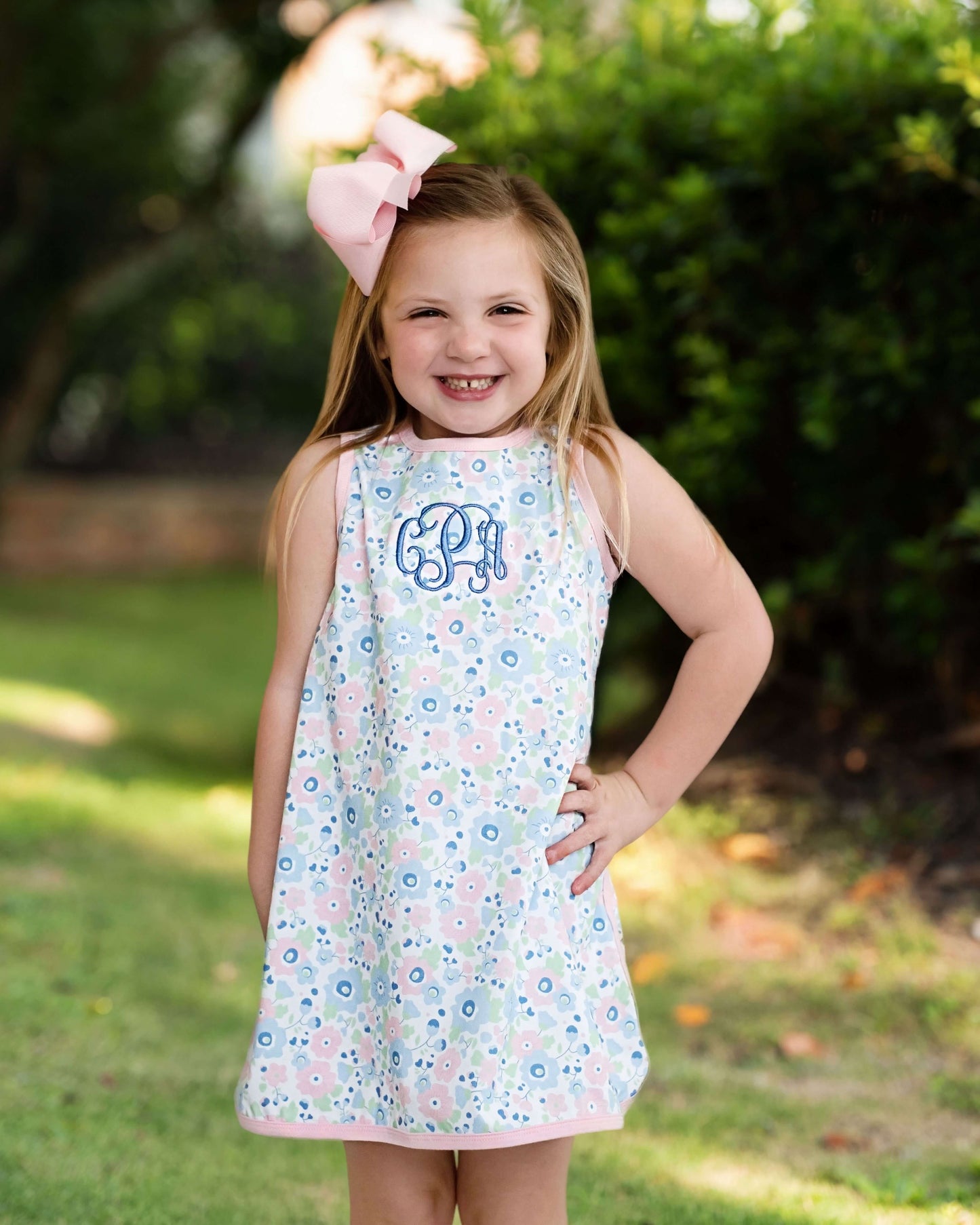 Young girl wearing a floral dress with a pink bow outdoors