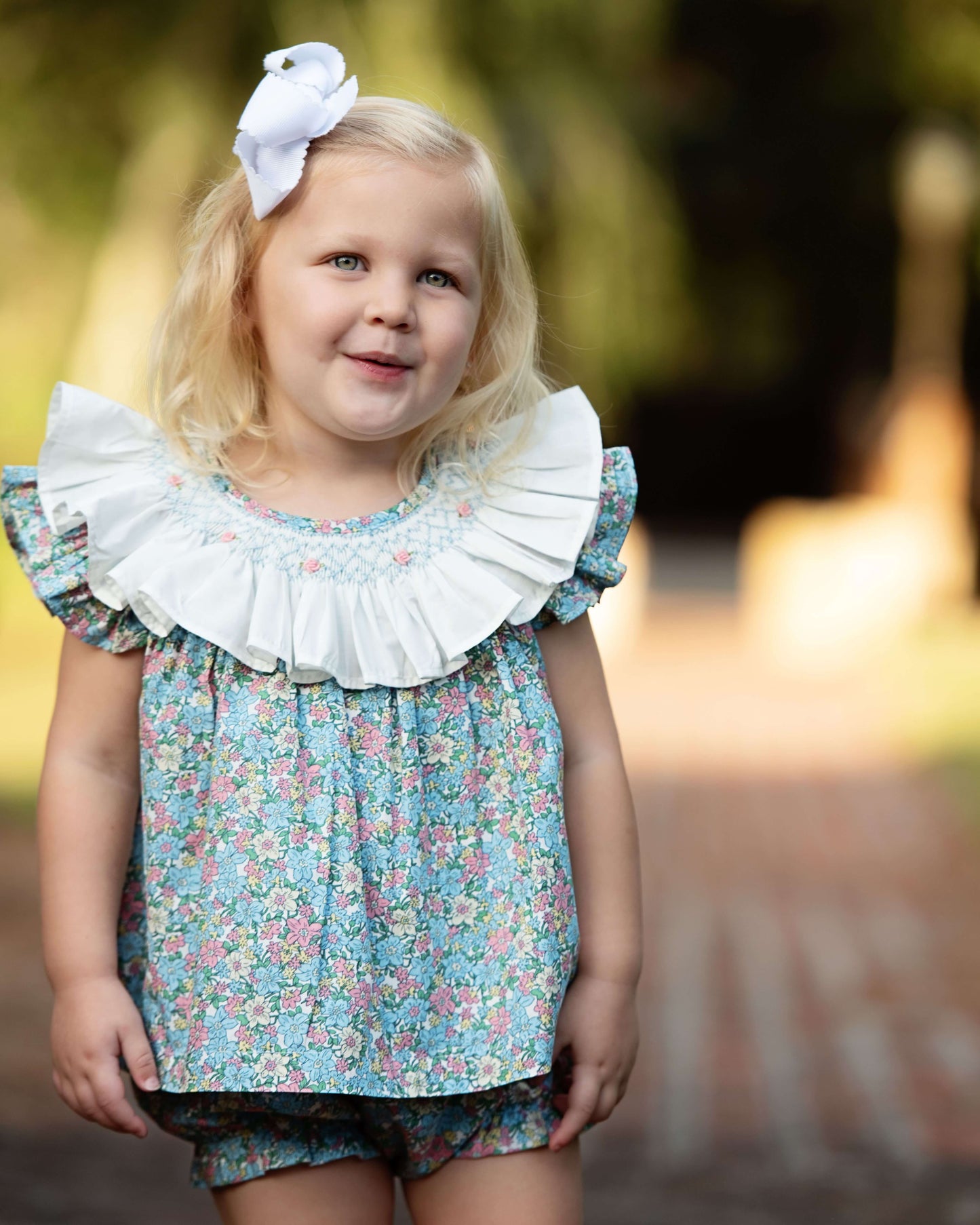 Young girl wearing a floral dress with ruffled collar outdoors