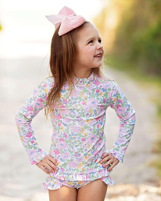 Young girl wearing a floral long-sleeve swimsuit with a blurred natural background