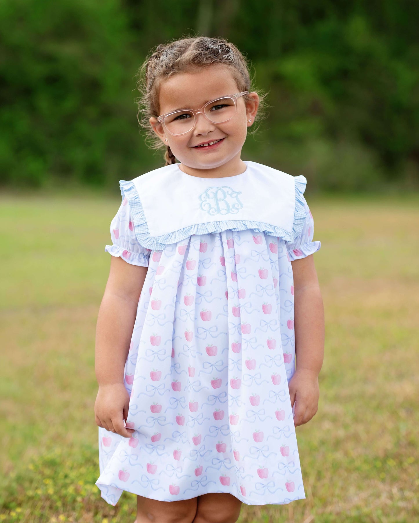 Young girl wearing a light blue dress with pink polka dots in an outdoor setting