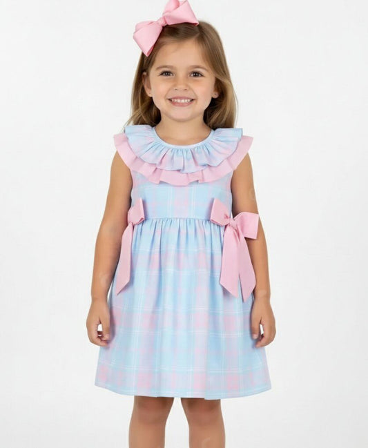 Young girl wearing a light blue dress with pink ruffles and bows on a white background