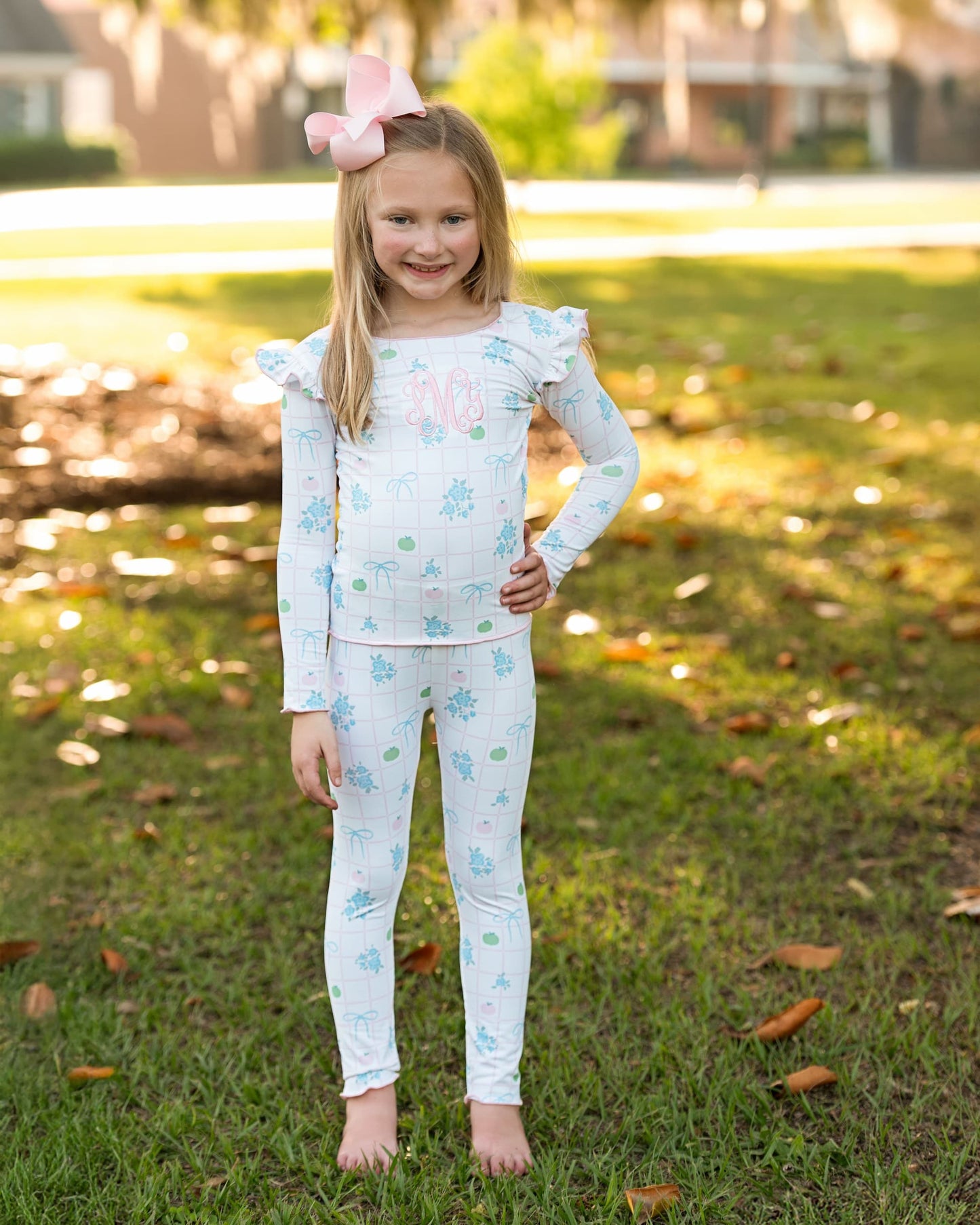 Young girl wearing a light blue pajama set with floral and pumpkin patterns outdoors.
