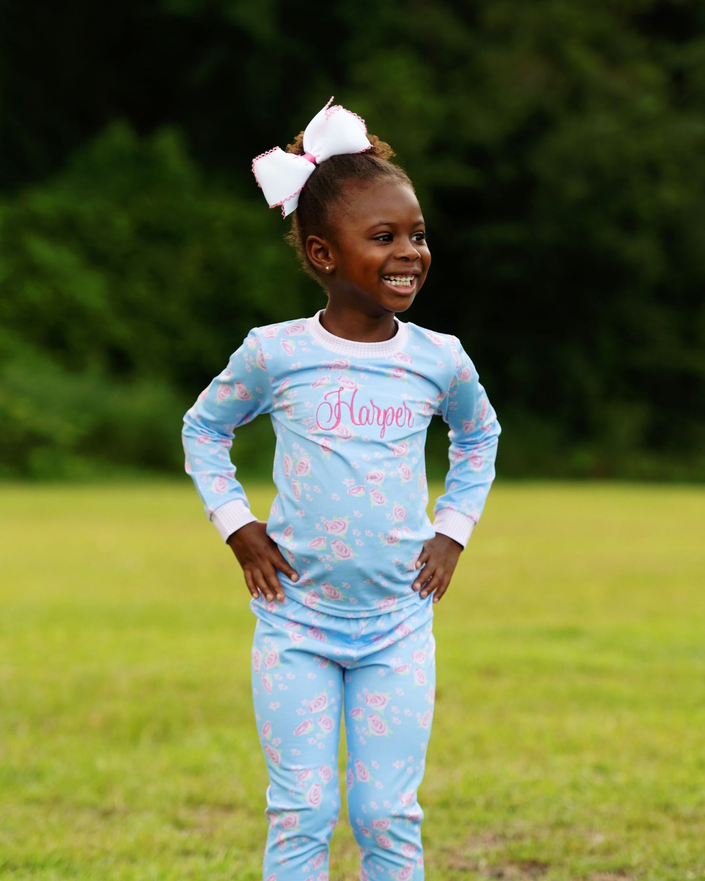 Young girl wearing a light blue pajama set with floral patterns outdoors.