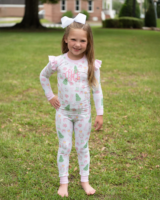 Young girl wearing a pajama set with a floral pattern outdoors on grass.