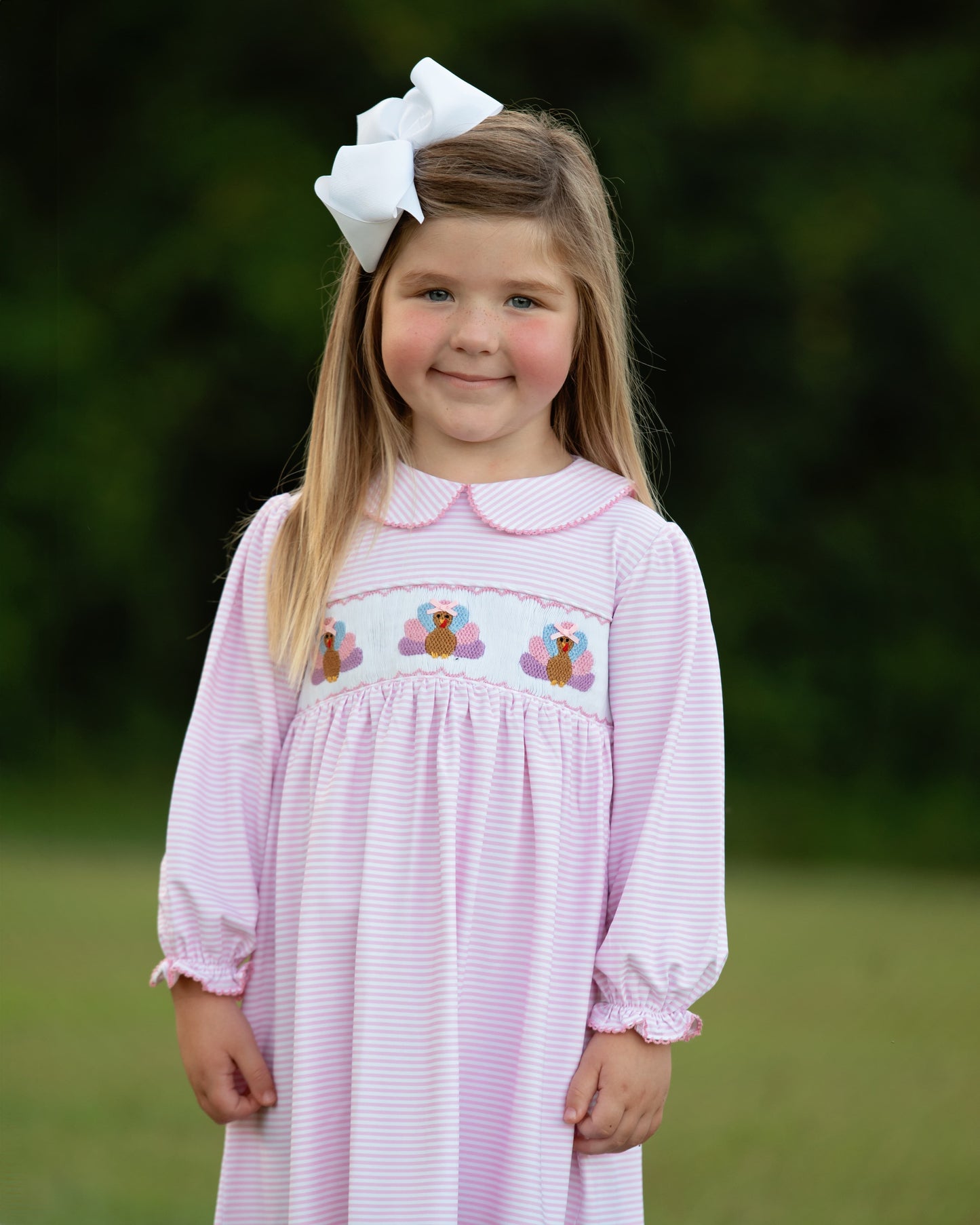 Young girl wearing a pink dress with turkey, standing outdoors 1