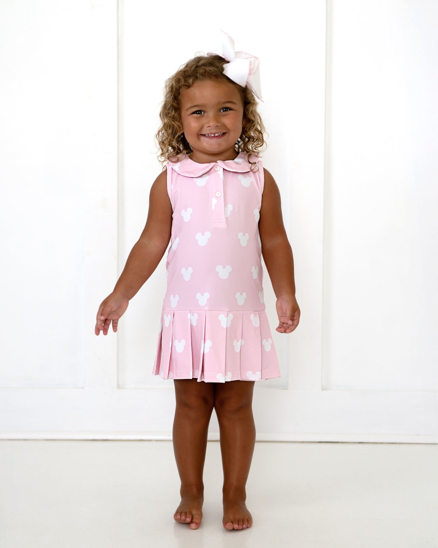 Young girl wearing a pink dress with white heart patterns on a white background