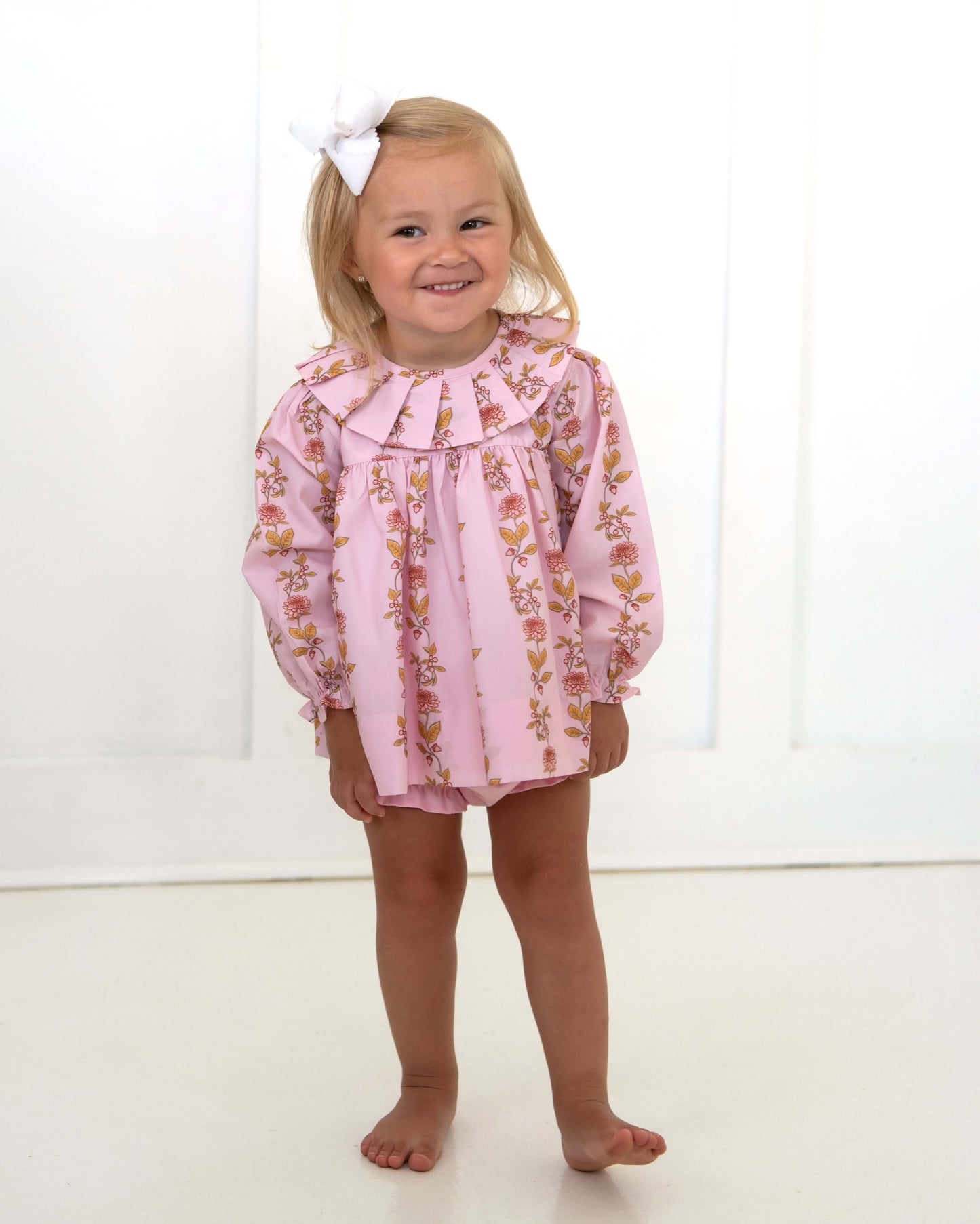Young girl wearing a pink floral dress with a white background