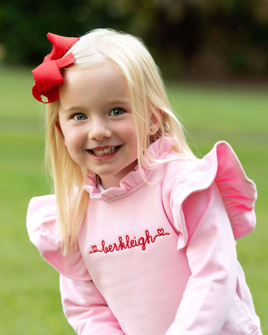 Young girl wearing a pink hoodie with 'berkshire' embroidered on it, standing outdoors.