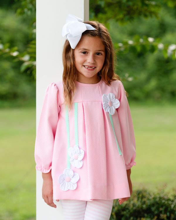 Young girl wearing a pink legging set with floral details outdoors