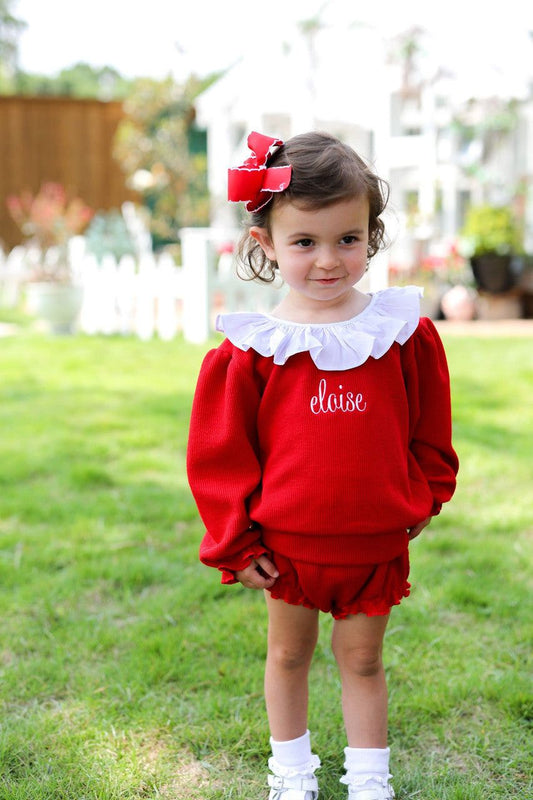 Young girl wearing a red outfit with a red bow on her hair