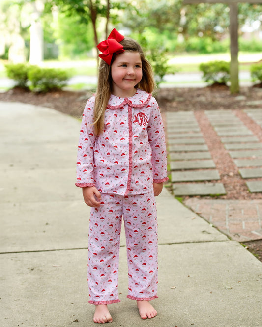 Young girl wearing pink flamingo pajamas with a red bow in a park setting
